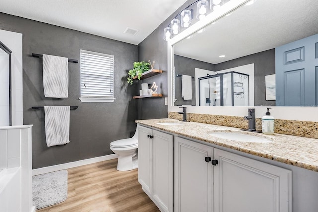 bathroom with toilet, wood-type flooring, an enclosed shower, and vanity