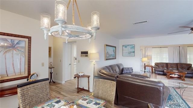 living room with ceiling fan with notable chandelier and light hardwood / wood-style flooring