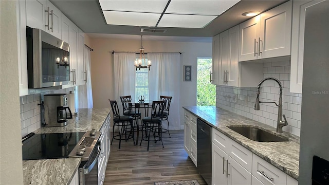 kitchen featuring appliances with stainless steel finishes, tasteful backsplash, light stone counters, sink, and white cabinetry