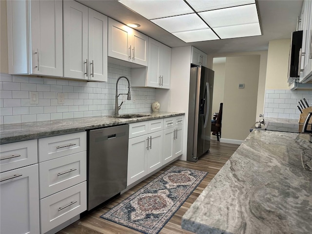 kitchen with light stone countertops, white cabinetry, sink, and appliances with stainless steel finishes