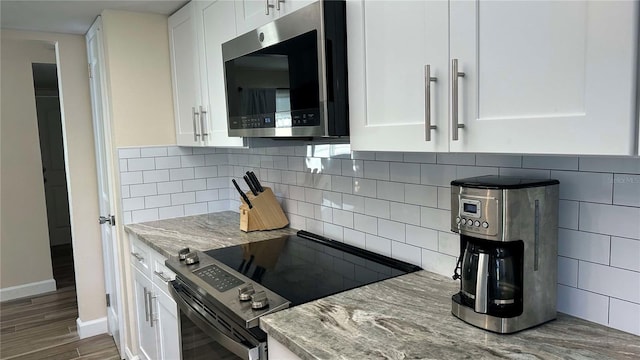 kitchen with white cabinets, stainless steel appliances, tasteful backsplash, and light stone countertops