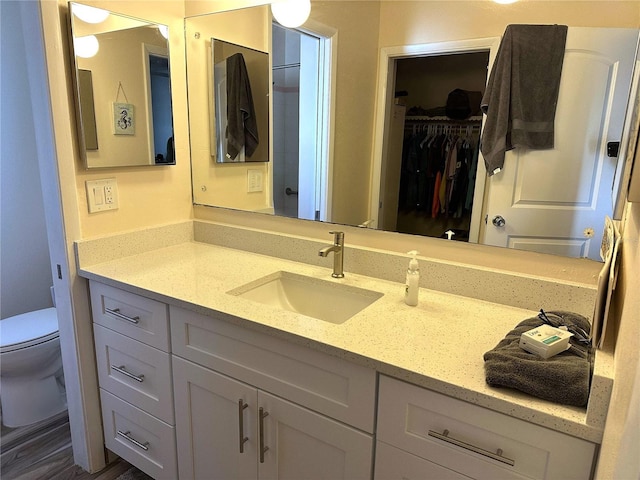 bathroom with hardwood / wood-style floors, vanity, and toilet