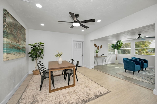 dining space with ceiling fan, light wood-type flooring, and a textured ceiling