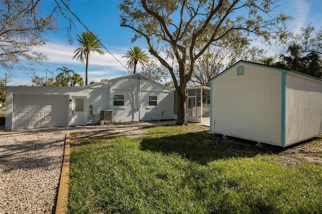 rear view of property with a yard, central AC unit, and a garage