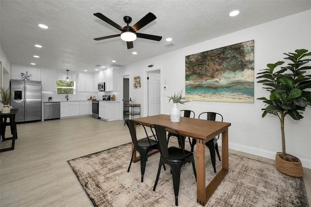 dining space with a textured ceiling, ceiling fan, and sink