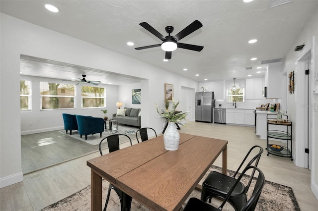 dining space with ceiling fan, light hardwood / wood-style flooring, and sink