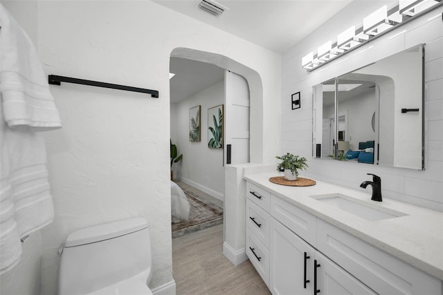 bathroom with hardwood / wood-style floors, vanity, and toilet