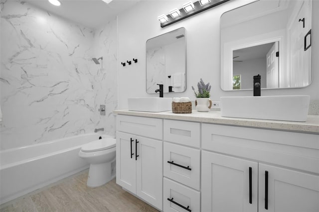 full bathroom featuring vanity, hardwood / wood-style floors, tiled shower / bath combo, and toilet