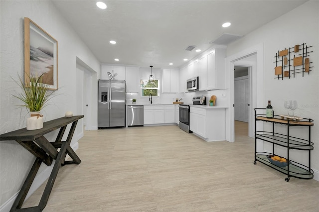 402 Pineapple St, Tarpon Springs, FL 34689 - kitchen with visible vents, light wood finished floors, appliances with stainless steel finishes, and white cabinetry