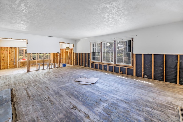 unfurnished room featuring a healthy amount of sunlight, hardwood / wood-style floors, and a textured ceiling