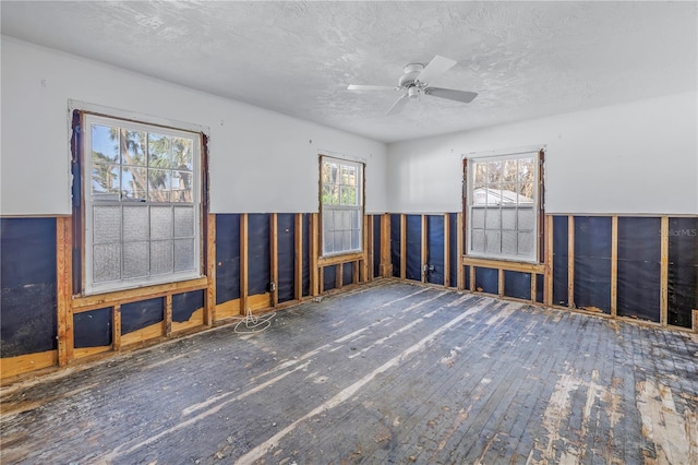 empty room featuring dark wood-type flooring, a textured ceiling, and ceiling fan