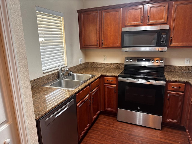 kitchen featuring dark countertops, dark wood-style floors, stainless steel appliances, and a sink