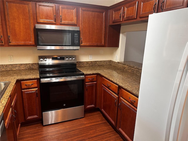 kitchen with dark stone countertops, stainless steel appliances, and dark wood-style flooring