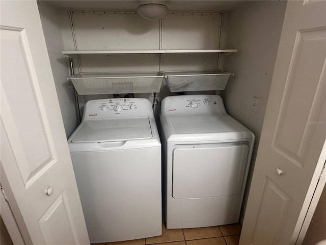 clothes washing area featuring laundry area, light tile patterned flooring, and washing machine and dryer