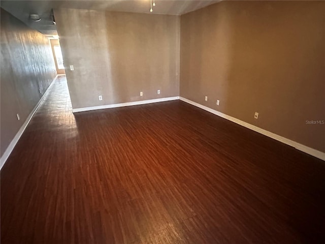 spare room featuring dark wood-style floors and baseboards