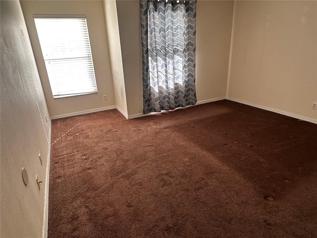 spare room featuring carpet floors and baseboards