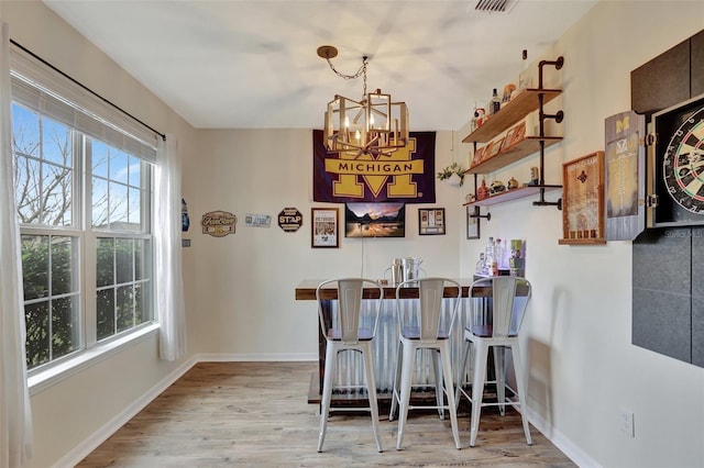 bar with pendant lighting, an inviting chandelier, and light hardwood / wood-style floors