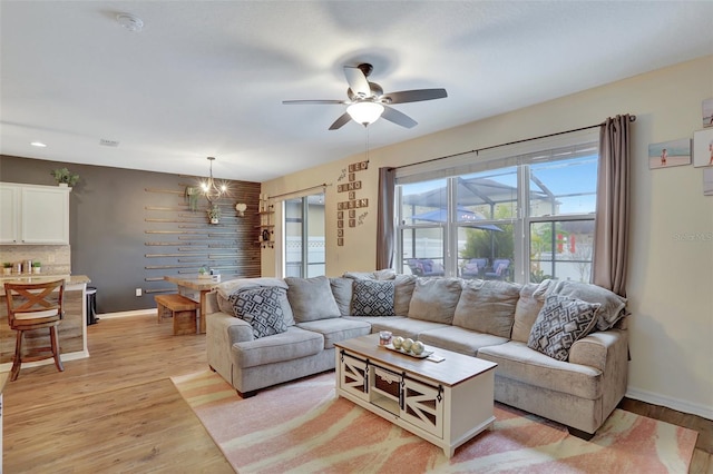 living room featuring light wood-type flooring and ceiling fan with notable chandelier