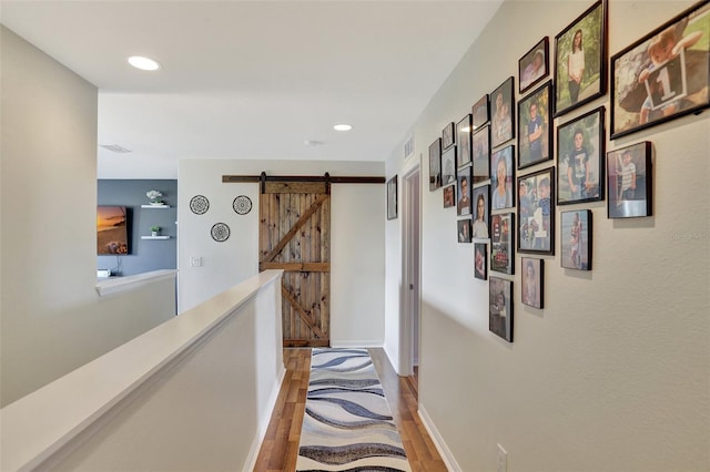 corridor featuring a barn door and hardwood / wood-style floors