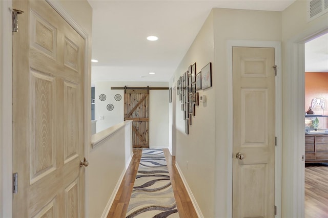 hallway featuring a barn door and light hardwood / wood-style flooring