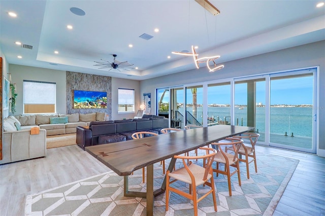 dining room featuring a raised ceiling, ceiling fan, and light hardwood / wood-style flooring