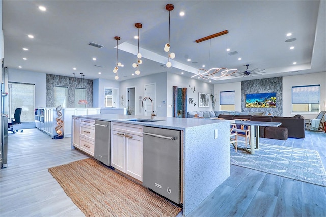 kitchen with white cabinetry, sink, a kitchen island with sink, ceiling fan, and light wood-type flooring