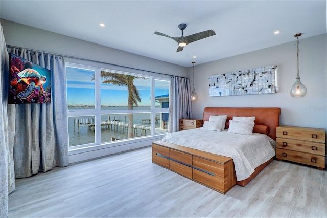 bedroom with a water view, ceiling fan, and light hardwood / wood-style floors