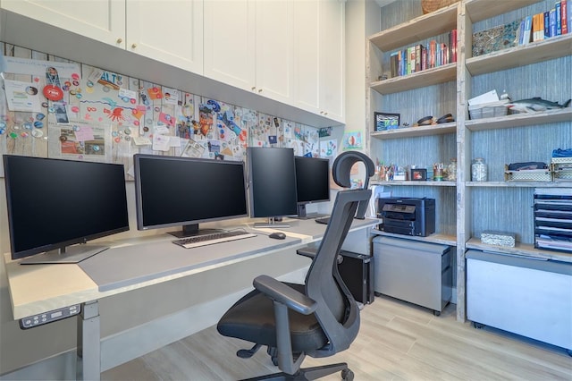 home office with built in desk and light hardwood / wood-style floors