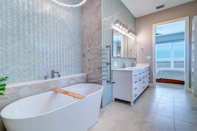 bathroom with a bath, vanity, and tile walls