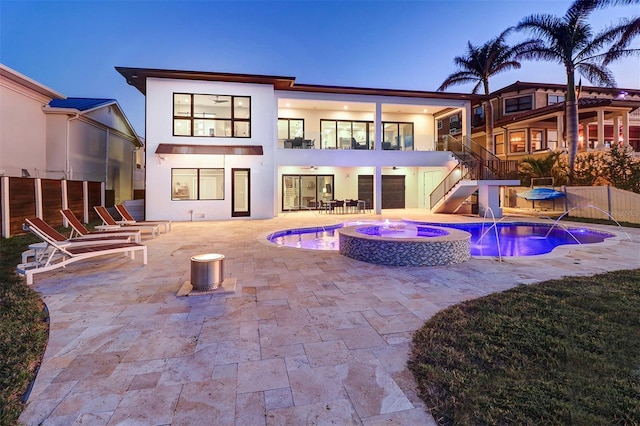 back house at dusk with a pool with hot tub, a patio area, and pool water feature