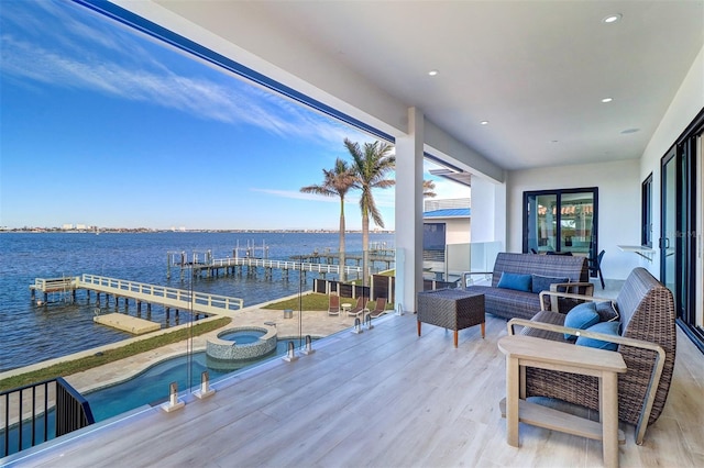 wooden deck featuring an outdoor living space, an in ground hot tub, and a water view