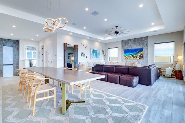 interior space with ceiling fan, a raised ceiling, and light hardwood / wood-style flooring