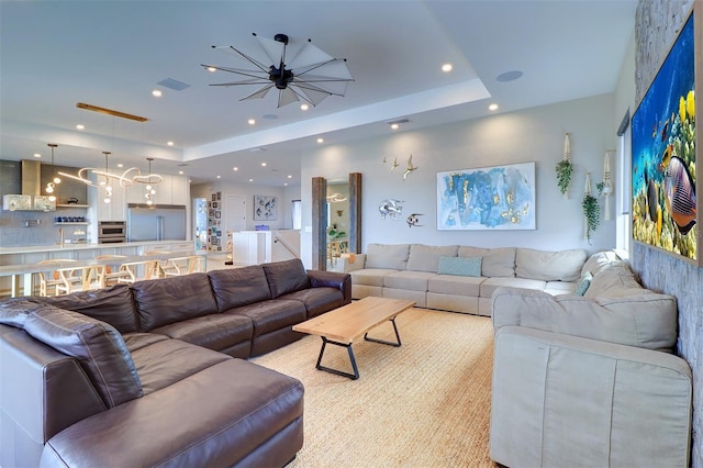 living room featuring ceiling fan and a raised ceiling