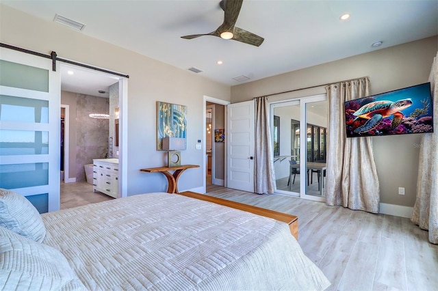 bedroom with ensuite bathroom, access to outside, ceiling fan, light hardwood / wood-style floors, and a barn door