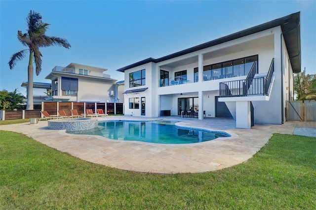 back of house featuring a balcony, a patio, a pool with hot tub, and a lawn