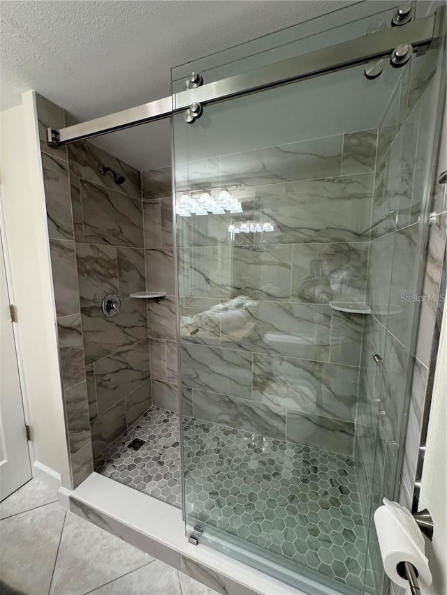 bathroom featuring a textured ceiling, tile patterned flooring, and a shower with door