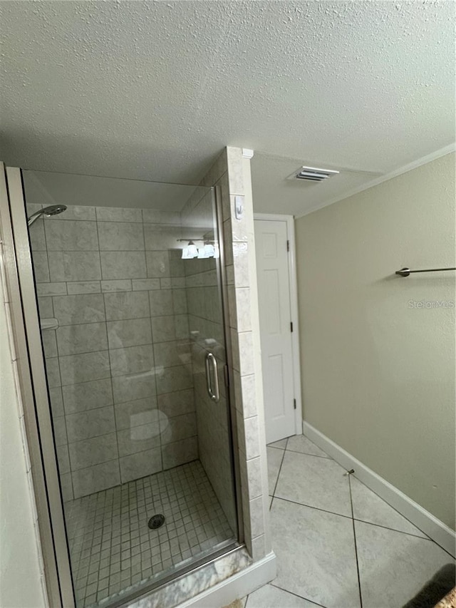 bathroom with a shower with shower door, a textured ceiling, and tile patterned flooring