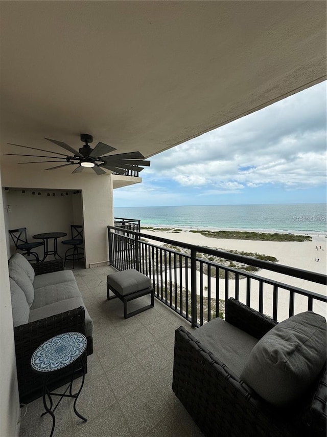 balcony with ceiling fan, a water view, and a view of the beach