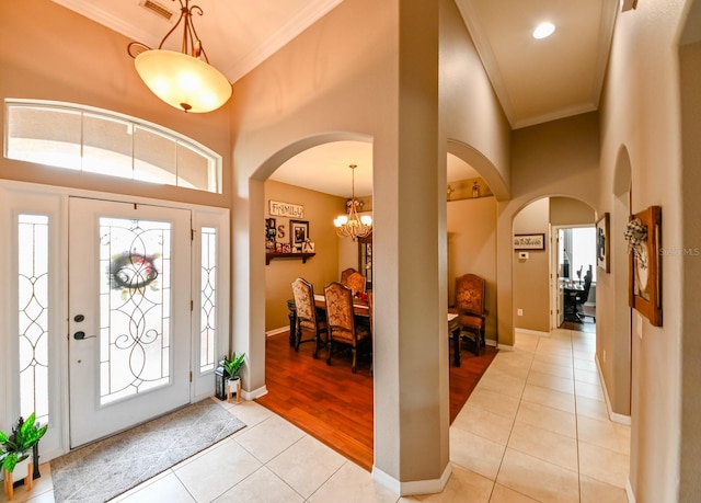 entrance foyer featuring a notable chandelier, ornamental molding, and light tile patterned floors