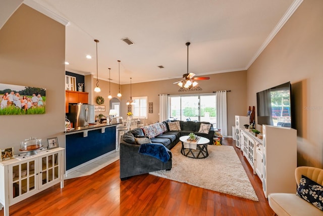 living room with hardwood / wood-style floors, ceiling fan, and ornamental molding