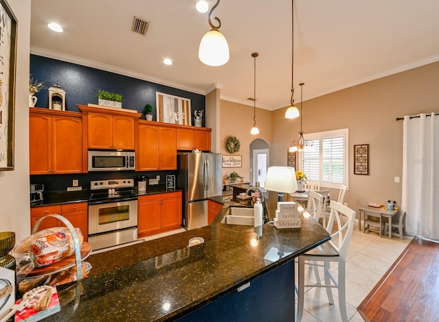 kitchen with appliances with stainless steel finishes, tasteful backsplash, hanging light fixtures, light tile patterned floors, and sink