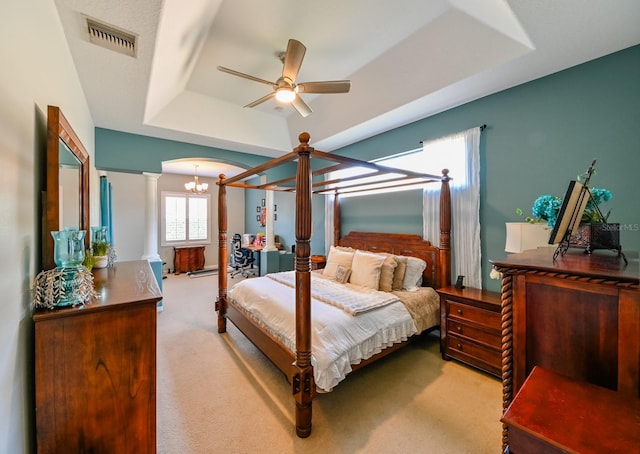 bedroom featuring decorative columns, ceiling fan, a raised ceiling, and light colored carpet