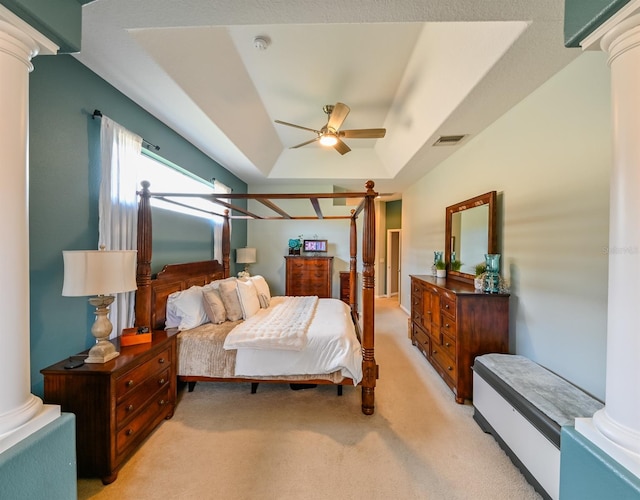 bedroom with ceiling fan, a tray ceiling, ornate columns, and light carpet