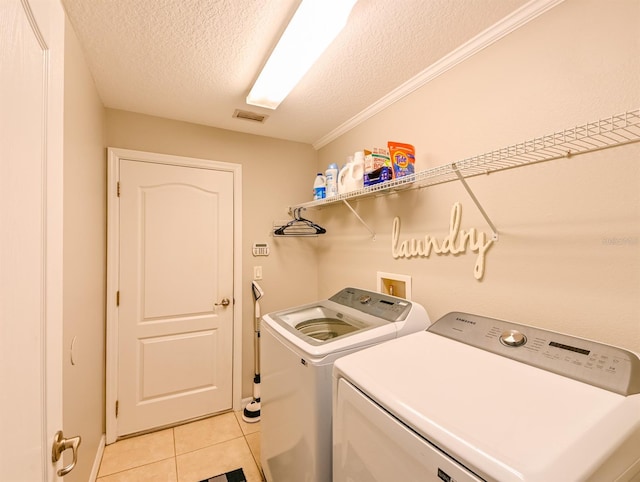 laundry area featuring separate washer and dryer, a textured ceiling, ornamental molding, and light tile patterned flooring