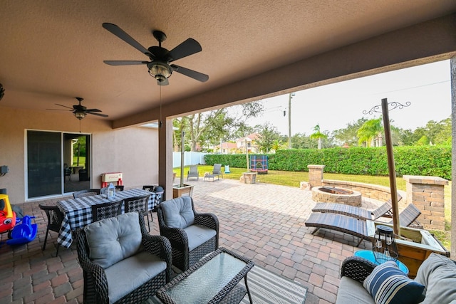 view of patio with ceiling fan and an outdoor living space with a fire pit