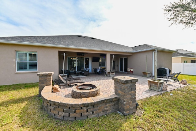 back of property featuring a lawn, an outdoor fire pit, and a patio