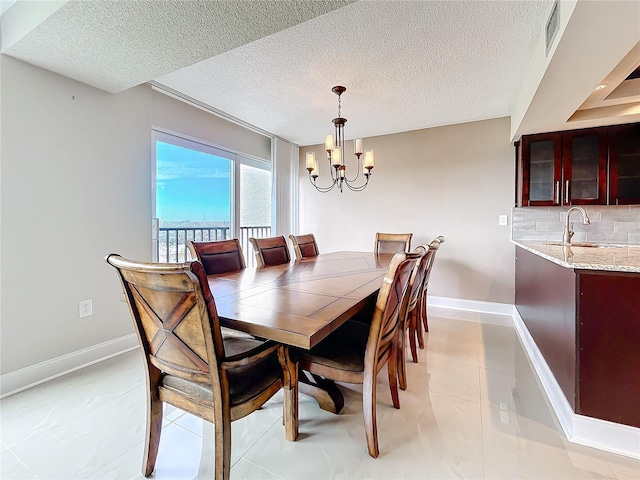 dining area with sink, a textured ceiling, and a notable chandelier