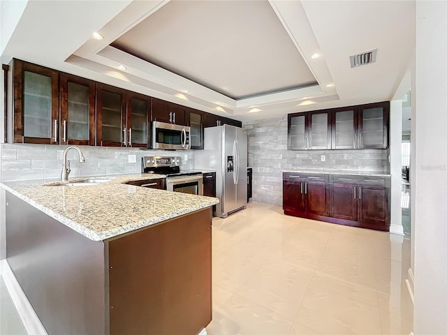 kitchen featuring a raised ceiling, kitchen peninsula, sink, and stainless steel appliances