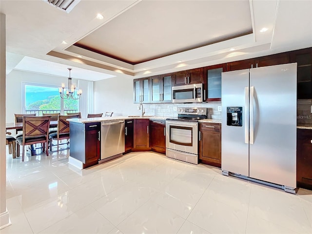 kitchen featuring a notable chandelier, decorative light fixtures, a raised ceiling, and appliances with stainless steel finishes