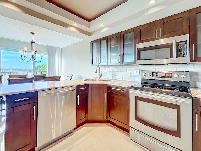 kitchen featuring an inviting chandelier, sink, decorative backsplash, light stone countertops, and stainless steel appliances